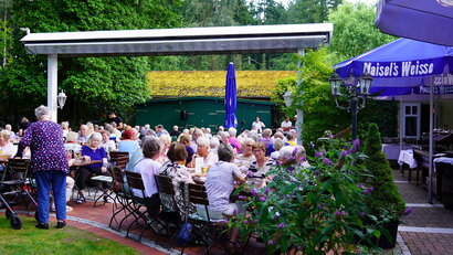 Viele Seniorinnen und Senioren genießen das Grillfest im Biergarten